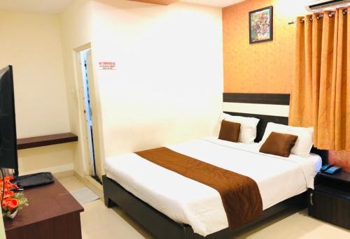 a bedroom with a bed and a desk and a television at Royal Residency in Pedappai