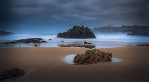 a beach with rocks in the sand and the ocean at Posada La Morena in Soto de la Marina