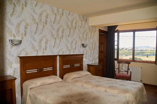 a bedroom with two beds and a wall with wallpaper at Posada La Morena in Soto de la Marina