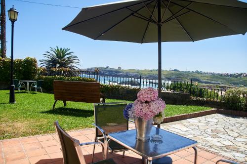 una mesa con un jarrón de flores y una sombrilla en Posada La Morena en Soto de la Marina