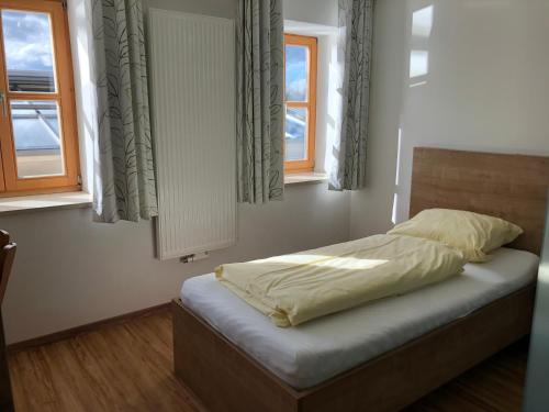 een bed in een slaapkamer met 2 ramen bij Fischerhof in Fahrenzhausen