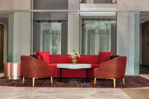 a red couch and two chairs and a table at Ramada Encore by Wyndham Muscat Al-Ghubra in Muscat