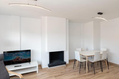 a white living room with a table and a tv at Hauzify I Apartament Big Family in Sant Feliu de Guíxols