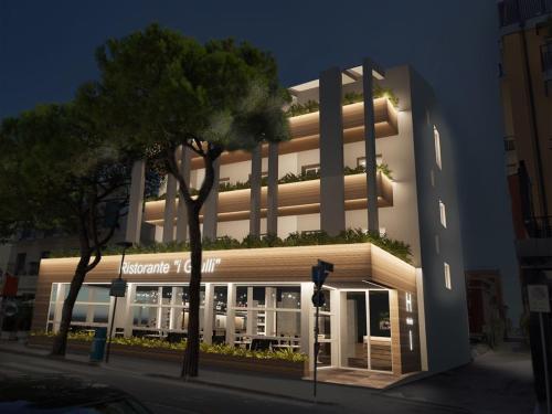 a large white building with trees in front of it at Hotel Ivana in Lido di Jesolo