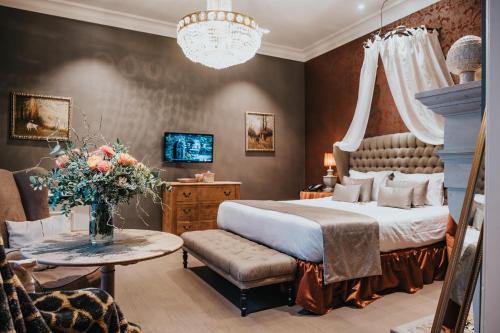 a bedroom with a bed and a table with a vase of flowers at Boutique Hotel De Castillion - Small elegant family hotel in Bruges