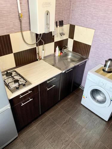Il comprend une petite cuisine avec un évier et un lave-linge. dans l'établissement Апартаменты в самом Центре прПобеды 90, à Tchernihiv