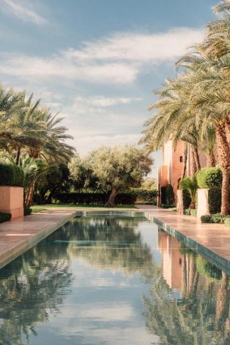 a pool of water with palm trees and a building at Amanjena Resort in Marrakech