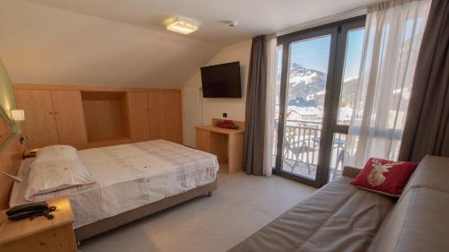 - une chambre avec un lit et une vue sur la montagne dans l'établissement Hotel Bellevue, à Canazei
