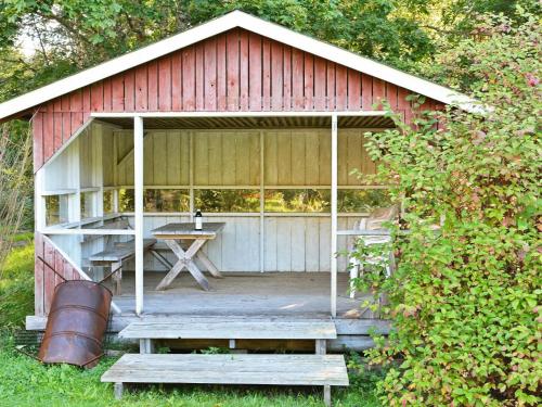 um barracão vermelho com uma mesa de piquenique e um banco em 8 person holiday home in L NSBODA em Ubbaboda