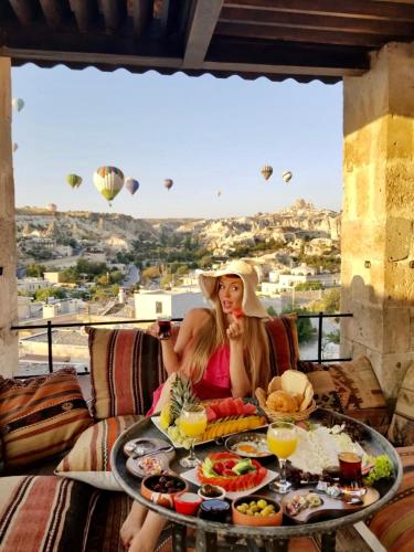 een vrouw aan een tafel met voedsel en luchtballonnen bij Doors Of Cappadocia Special Cave Hotel in Goreme