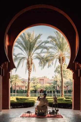 a man riding a camel through an arch with palm trees at Amanjena Resort in Marrakech