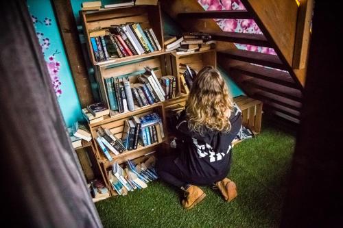 a girl sitting on the floor in front of a book shelf at Balmers Hostel in Interlaken