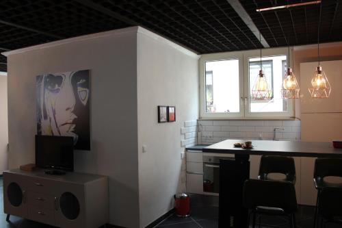 een kamer met een keuken, een bureau en een televisie bij BLUE SKY-Suite in Fellbach