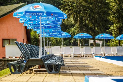 a group of chairs and umbrellas next to a pool at Pensiunea Mayumi Moneasa in Moneasa