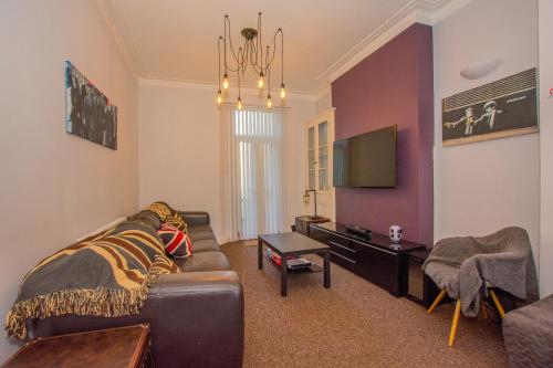 a living room with a couch and a tv at By Lushlets - City Centre Hot tub Pool table - Great for Hens Stags & Rugby groups! in Cardiff