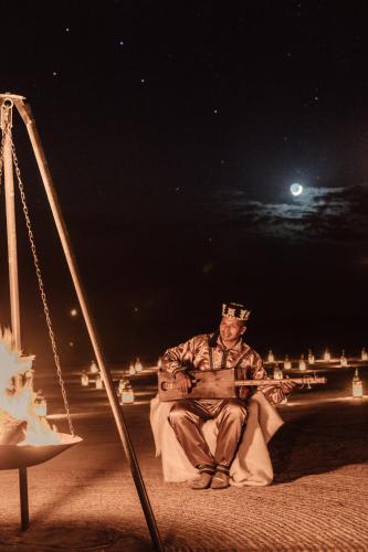 a man wearing a crown sitting on a swing at night at Amanjena Resort in Marrakech