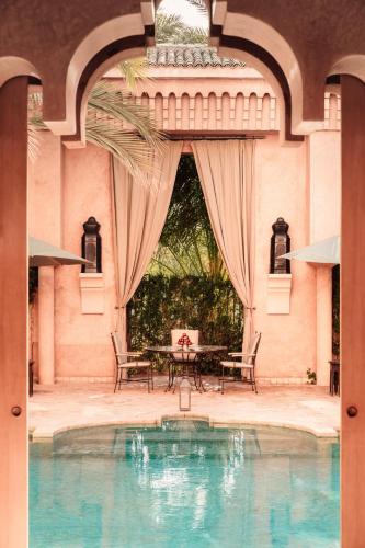 a pool in a building with a table and chairs at Amanjena Resort in Marrakech