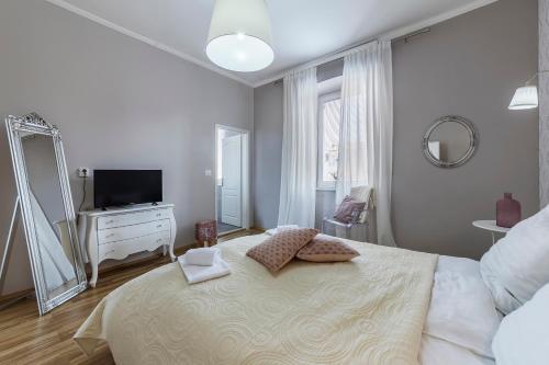 a white bedroom with a large bed and a mirror at Captain Emo City Apartments in Pula