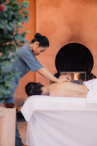 a woman getting a massage in front of a fireplace at Amanjena Resort in Marrakech