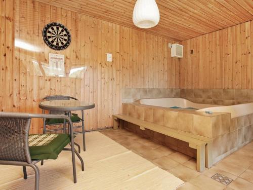 ブラーバンドにあるThree-Bedroom Holiday home in Blåvand 14のバスタブ、テーブル、椅子が備わります。