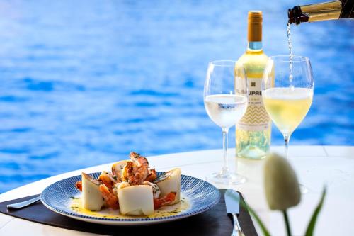 a plate of food and two glasses of wine on a table at Vidam Hotel Aracaju - Transamerica Collection in Aracaju