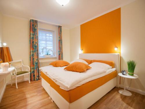 ein Schlafzimmer mit einem Bett mit einer orangefarbenen Wand in der Unterkunft Dünenpark Binz - Komfortplus Ferienwohnung mit 1 Schlafzimmer und Terrasse im Erdgeschoss 128 in Binz