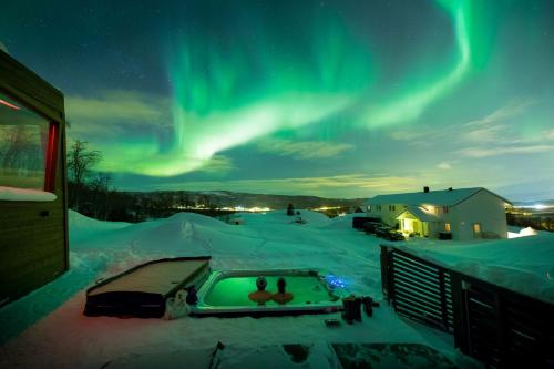 a view of the aurora over a snow covered yard with a pool at Aurora Borealis Observatory in Silsand