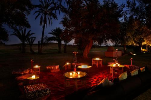 a group of tables and chairs with candles at night at Amanjena Resort in Marrakech