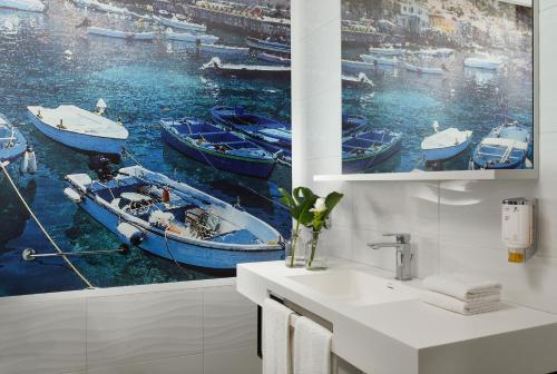 a bathroom with a painting of boats in the water at Falkensteiner Club Funimation Garden Calabria in Curinga