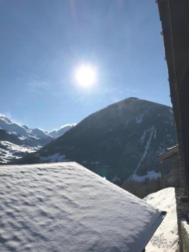 a view of a snow covered mountain with the sun in the sky at Chalet Le Biolley 2 in Orsières