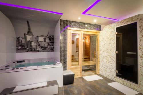 La salle de bains est pourvue d'une baignoire avec un éclairage violet. dans l'établissement L'Empire Paris - Louvre, à Paris