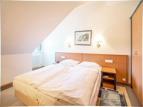 ein Schlafzimmer mit einem großen weißen Bett und einem Tisch in der Unterkunft Dünenpark Binz - Komfort Ferienwohnung mit 1 Schlafzimmer und Balkon im Dachgeschoss 234 in Binz