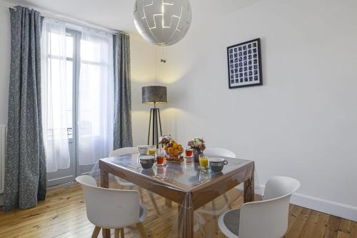 une salle à manger avec une table en bois et des chaises blanches dans l'établissement Appartement Sereno - Welkeys, à Biarritz