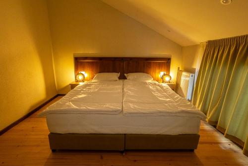 a bedroom with a large bed with two lamps on the side at Вила Добро поле in Blagoevgrad