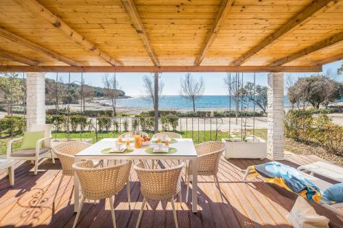 een tafel en stoelen op een terras met uitzicht op de oceaan bij Camping Homes Mon Perin in Bale