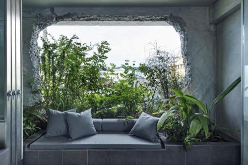 a couch sitting in front of a window with plants at hotel sou #sou in Goto