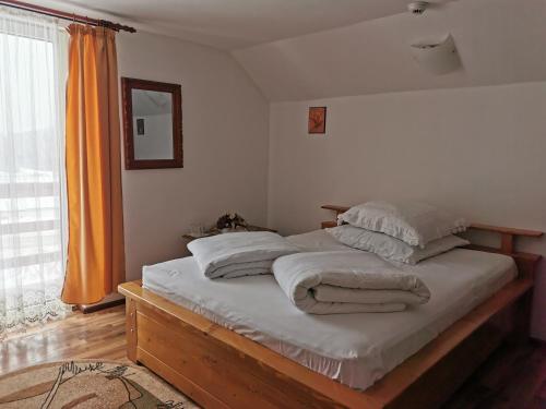 a bedroom with a bed with white sheets and pillows at Pensiunea Bradet - Padis in Padis