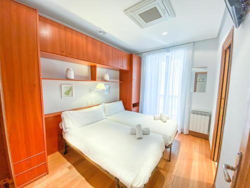 ein kleines Schlafzimmer mit einem weißen Bett und einem Fenster in der Unterkunft Habitaciones Turisticas Ayuntamiento San Sebastian in San Sebastián