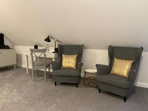 a living room with two chairs and a table with a lamp at Pałac Łochów in Łochów