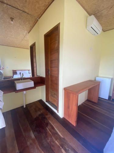 a bathroom with a sink and a wooden door at Amar Pousada in Luis Correia