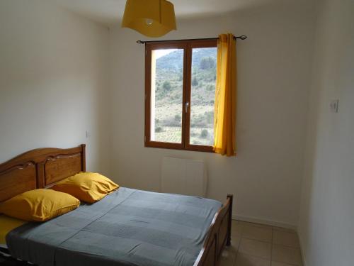 a bedroom with a bed with yellow pillows and a window at Gîte la tramontane in Cucugnan