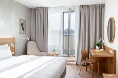 a hotel room with a bed, desk, and window at Botanique Hotel Prague in Prague