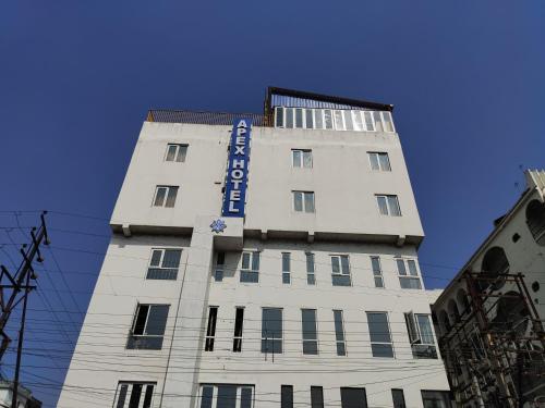 a tall white building with a blue sign on it at STAYMAKER Apex Hotel in Baharampur