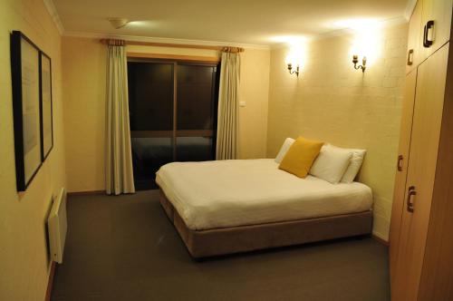 a bedroom with a bed with white sheets and yellow pillows at Salzburg Apartments in Perisher Valley