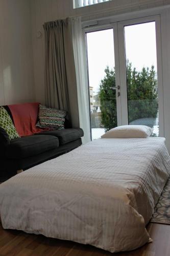a bedroom with a bed and a couch and a window at Bålsta Studio Houses in Bålsta