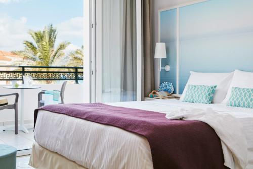 a bedroom with a bed and a table and a balcony at Caldera Beach in Plataniás