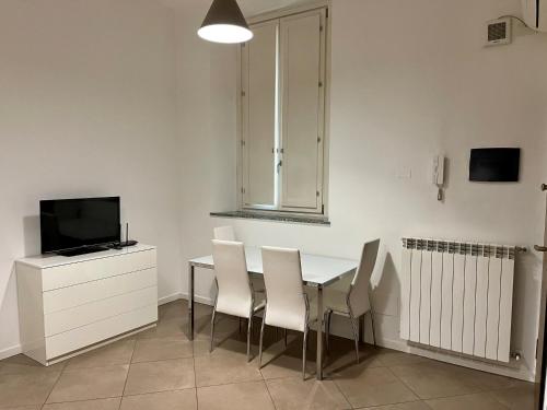 a dining room with a table and chairs and a television at Easy Milano - Rooms and Apartments Navigli in Milan