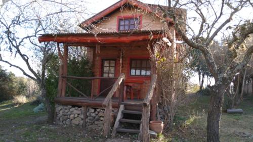 a small log cabin with a staircase leading up to it at Los Arbolitos Cabañas y Aparts in Santa Rosa de Calamuchita