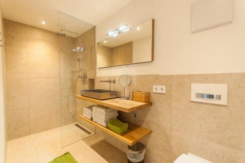 uma casa de banho com um chuveiro, um lavatório e um espelho. em Chalet Max Panorama by we rent em Zell am See