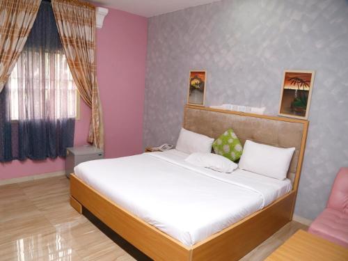 a bedroom with a bed with white sheets and pink walls at Nera Hotels in Jabi